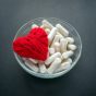 White,Veg,Capsules,And,Red,Thread,Heart,In,Glass,Bowl